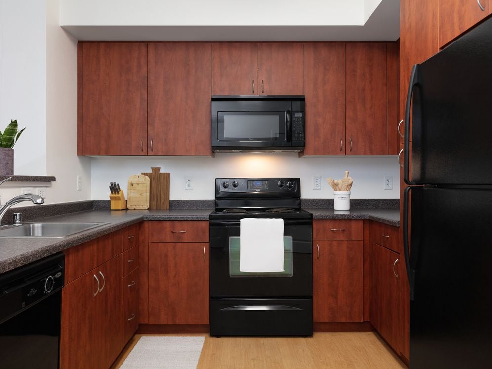 Classic Package I kitchen with black appliances, grey laminate countertops, cherry cabinetry, and hard surface flooring