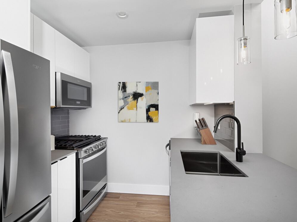 Renovated Package I kitchen with stainless steel appliances, white cabinetry, grey tile backsplash, grey quartz countertops, and hard-surface flooring (Representative Imagery)