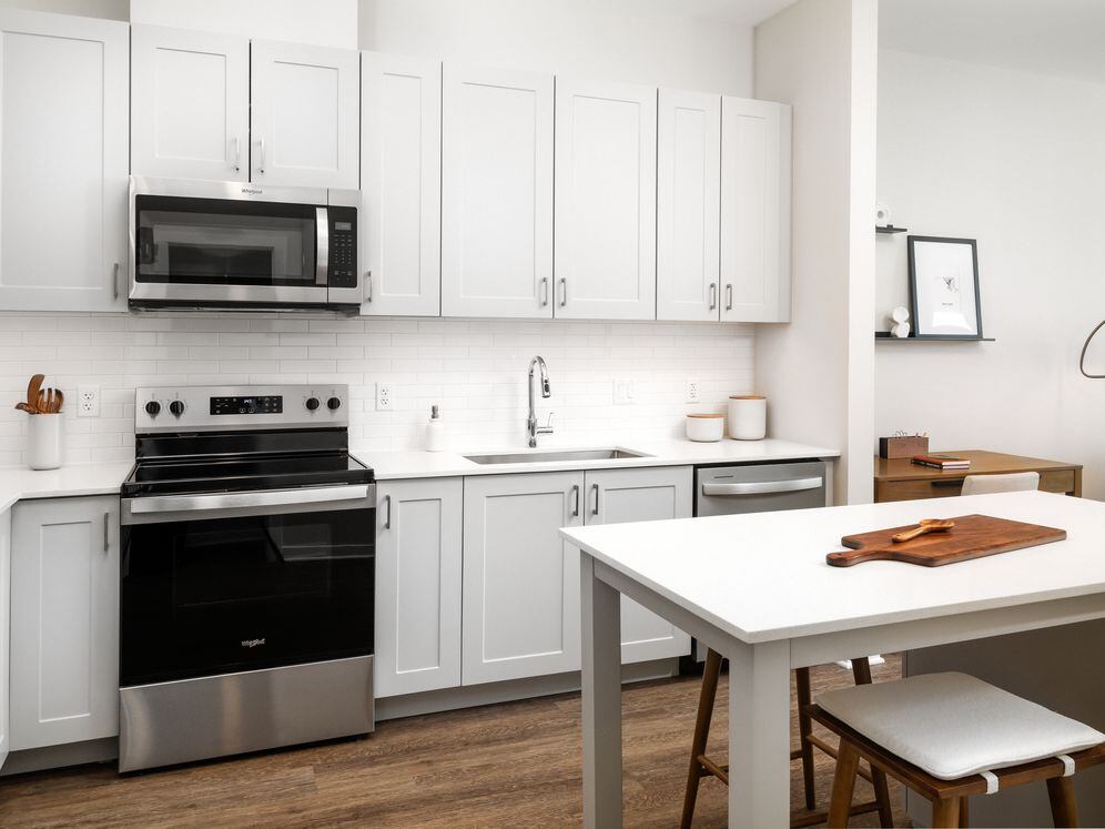 New West Phase apartments - Finish Package III Kitchen with stainless steel appliances, white quartz countertops, grey cabinetry, pendant lighting, and hard surface flooring