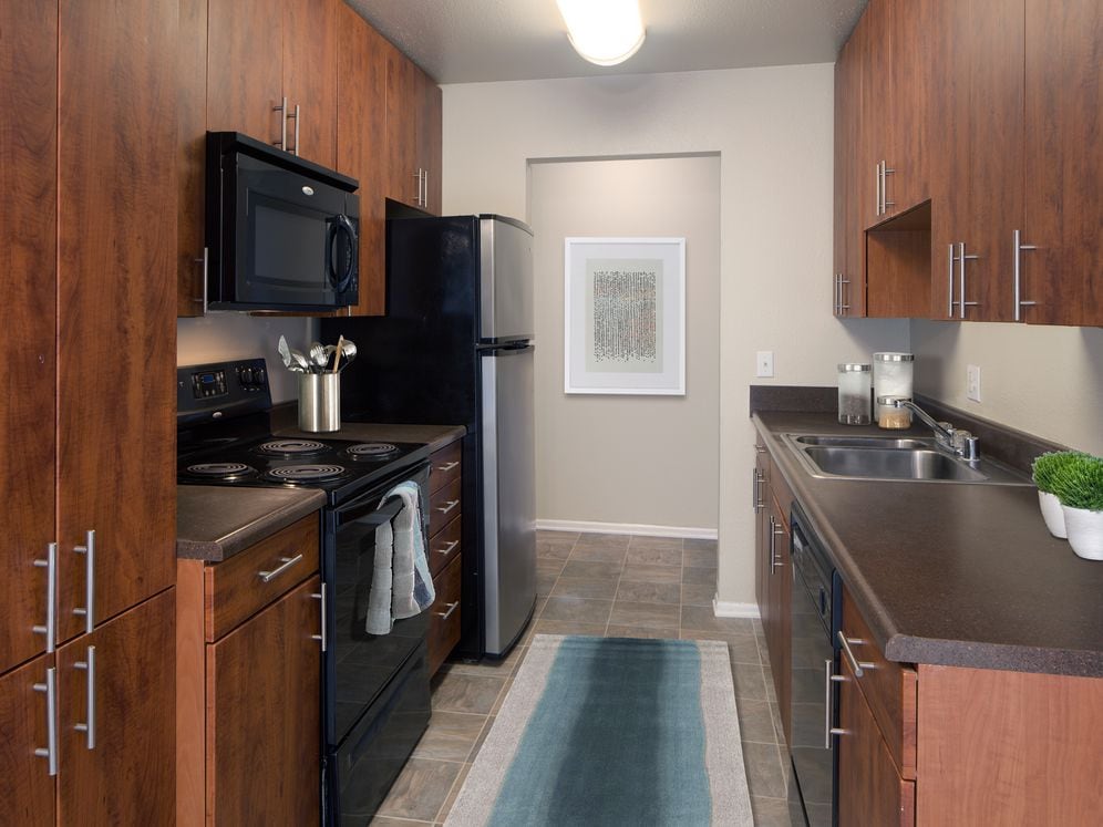 Classic Package II kitchen with dark laminate countertops, cherry cabinetry, black appliances, and hard surface flooring