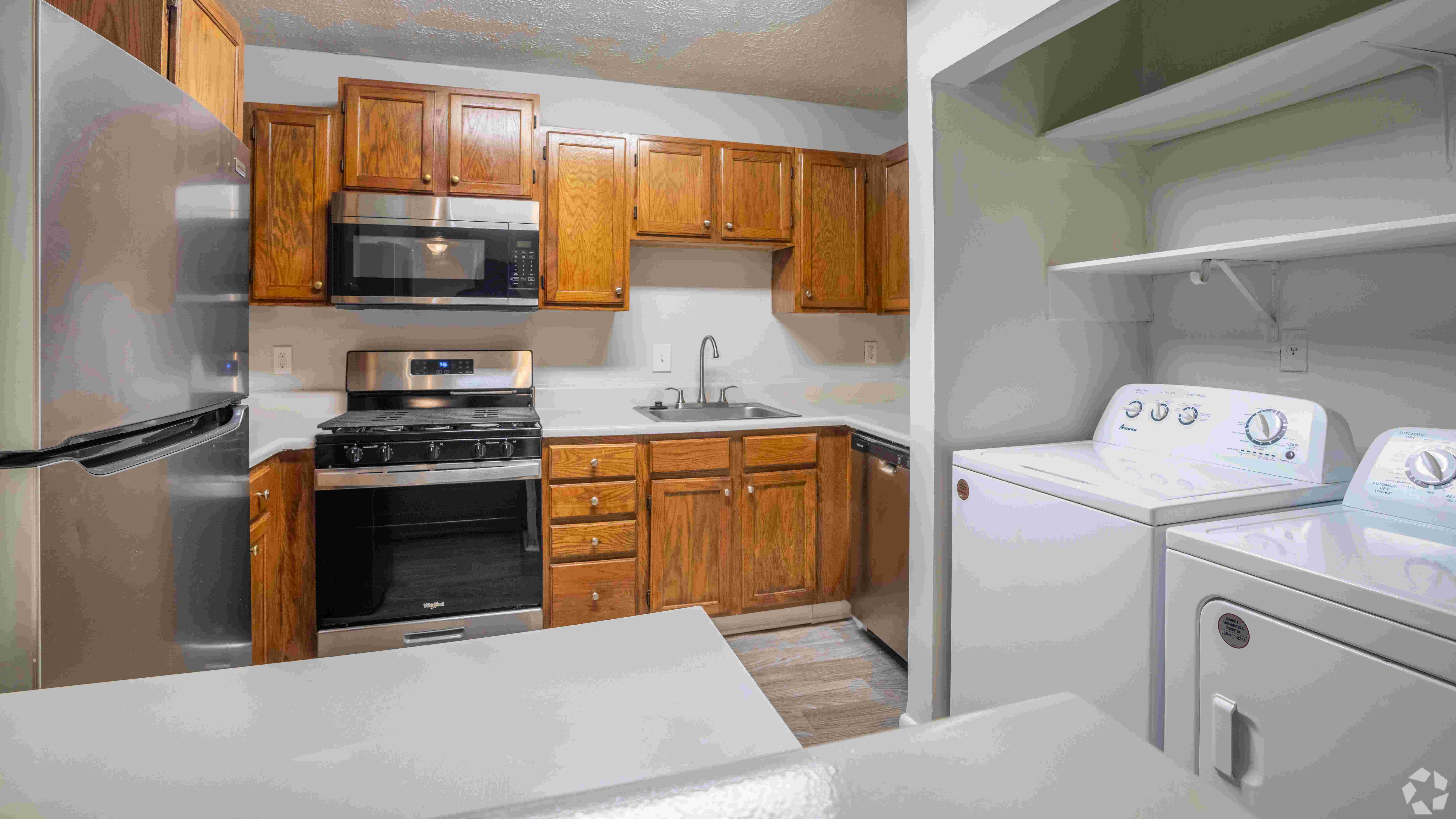 Kitchen featuring stainless steel appliances, warm wood cabinetry, and an in-unit washer and dryer for your convenience.