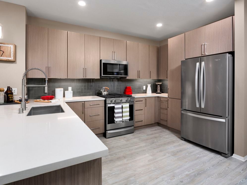 Design Scheme II Kitchen with quartz countertops, stainless steel appliances, and hard surface plank flooring