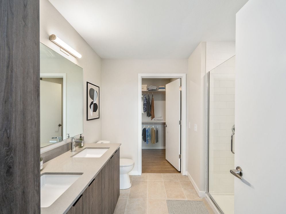 Signature Collection bath with marbled quartz countertop, double vanity, LED lighted vanity mirror, and tile flooring.