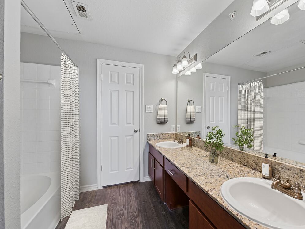 Bath with chestnut cabinetry, speckled granite countertops, and hard surface flooring