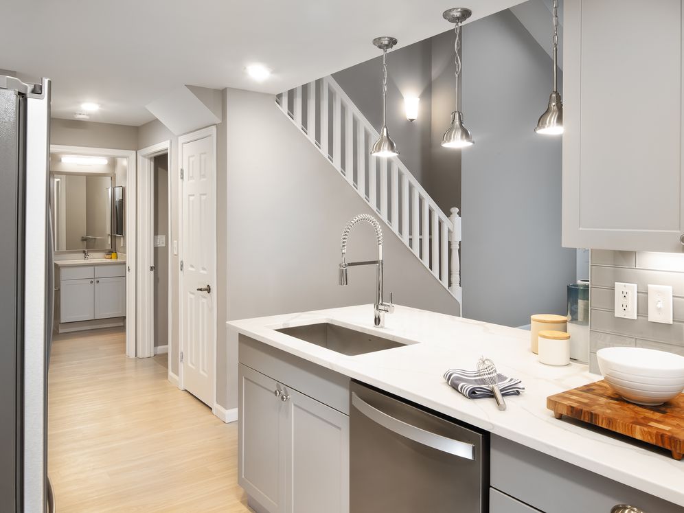 Premier Finish kitchen with grey cabinetry, white quartz countertops, stainless steel appliances, and hard surface flooring