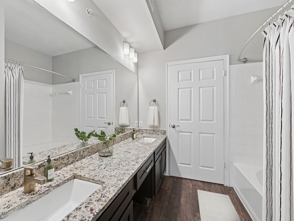 Bath with espresso cabinetry, speckled granite countertops, and hard surface flooring