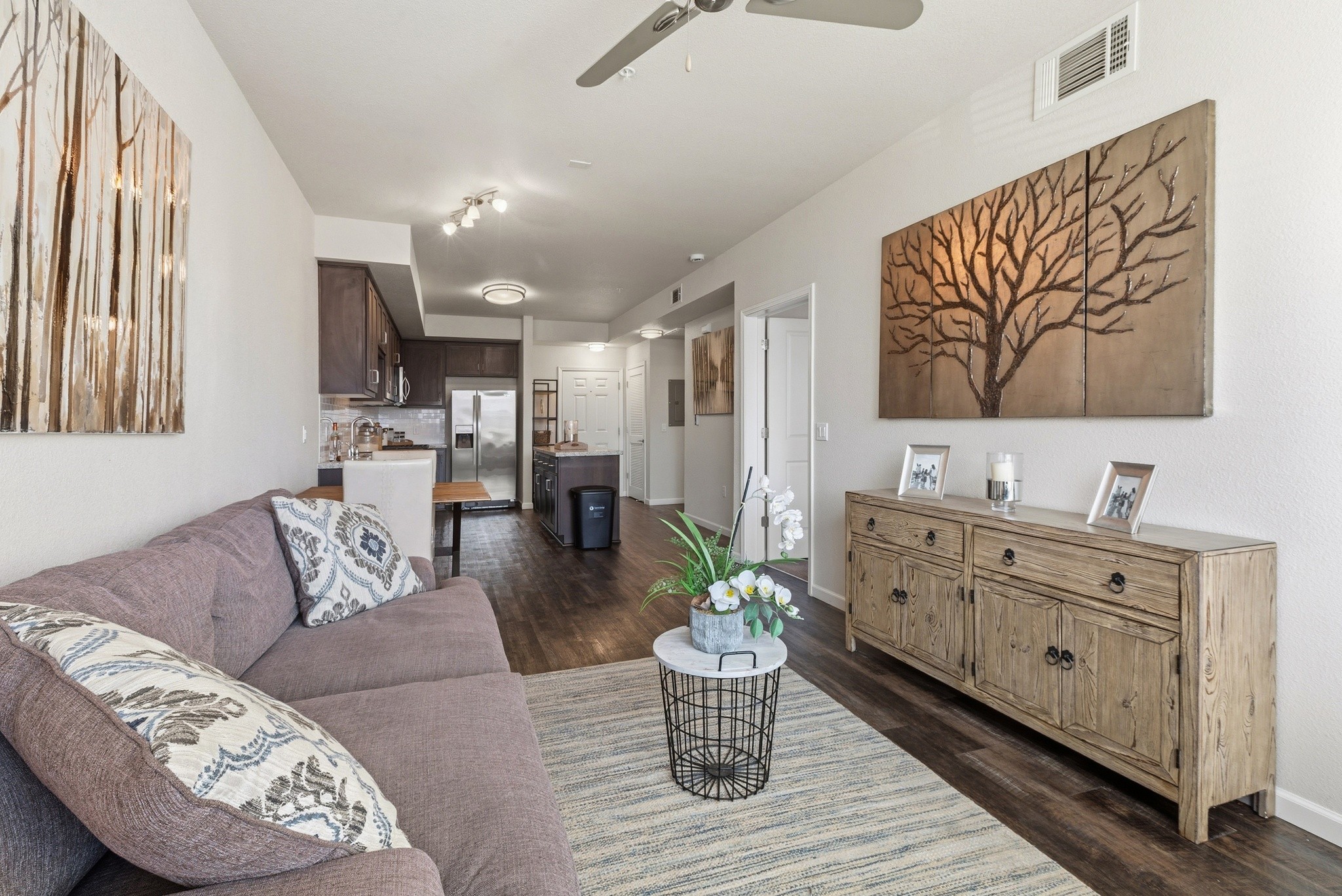 Aspire Apartments Tracy CA A living room with a blue chair and a painting of a tree on the wall.