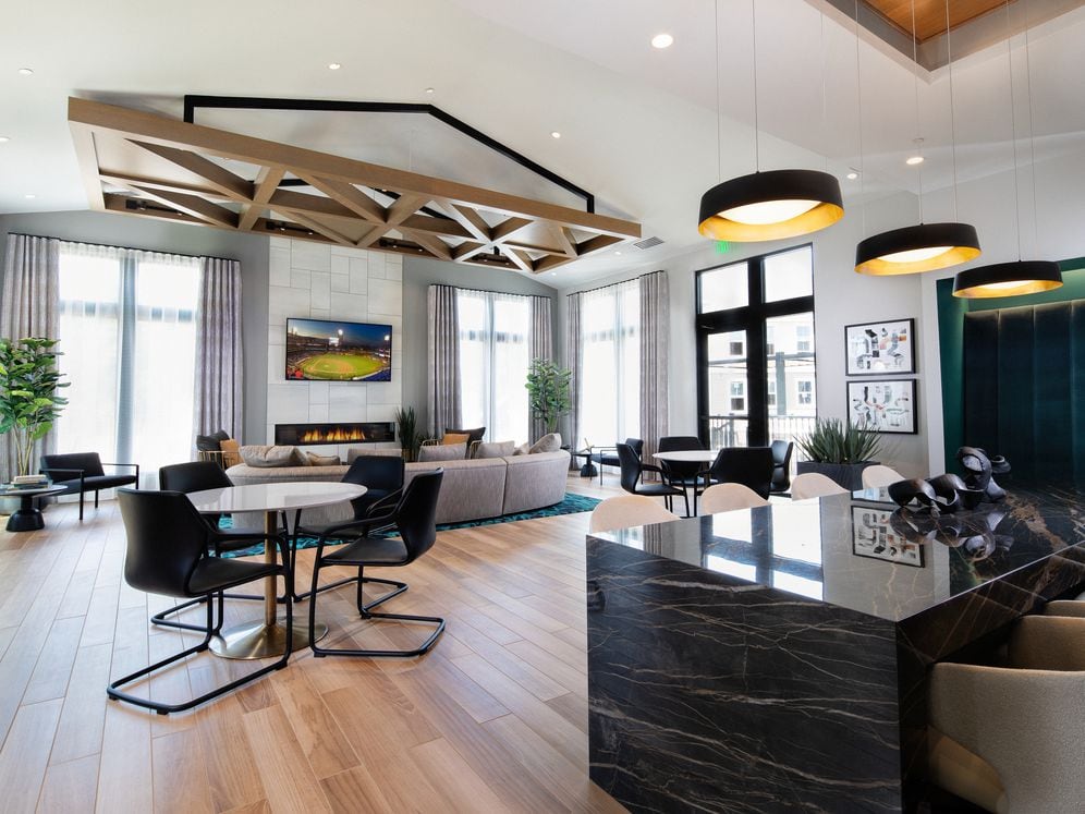 Resident lounge with multiple seating areas, TV, fireplace, and entertaining kitchen