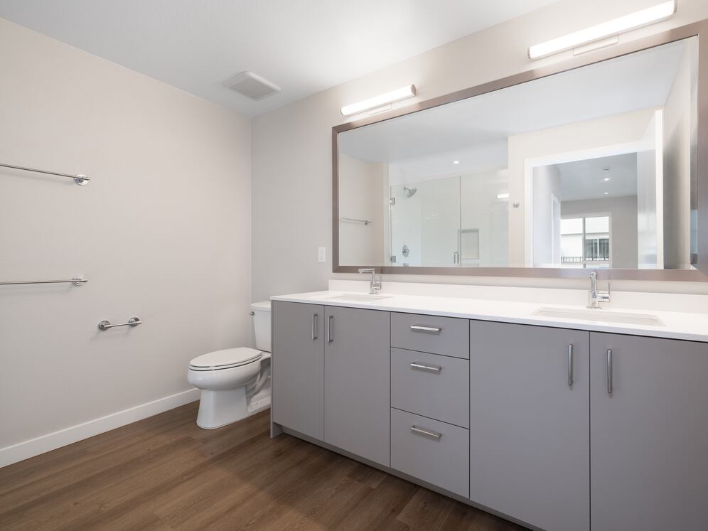 Upgrade Collection Primary bath with dual vanity sink, white quartz countertops, and hard-surface vinyl plank flooring