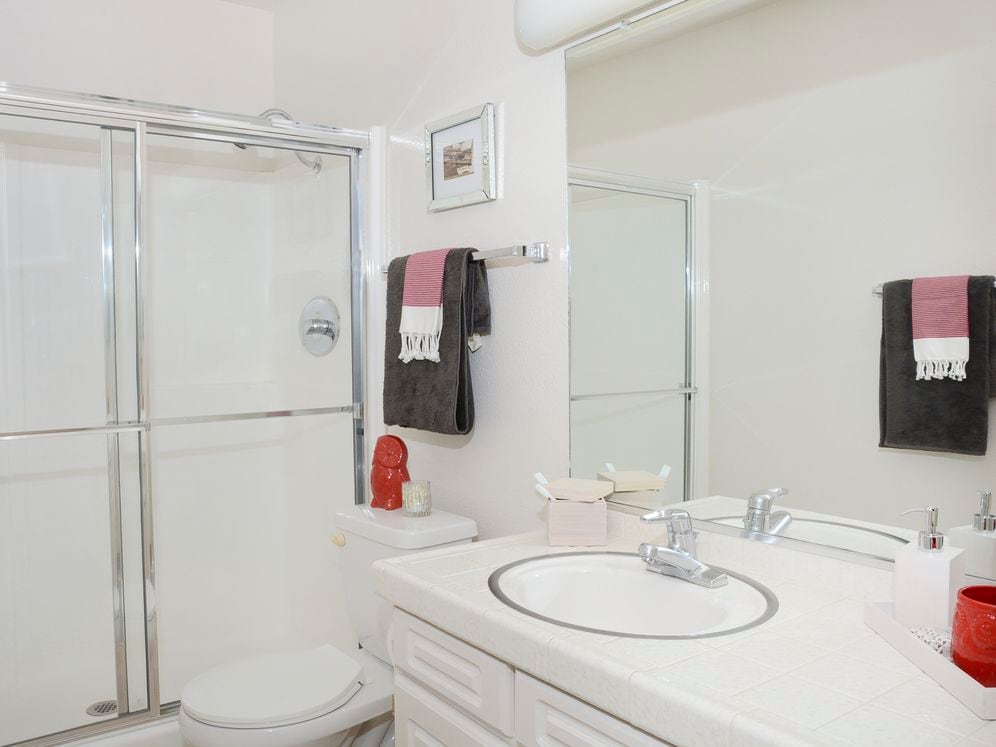 Classic Package bath featuring white tile countertops and white cabinetry