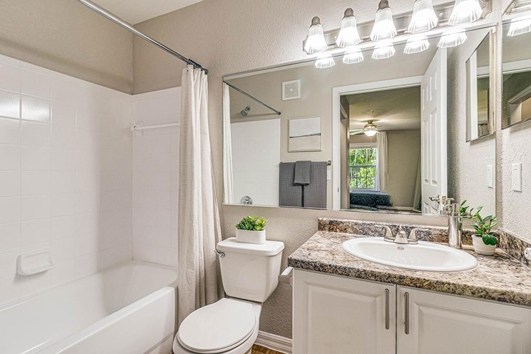 Bright bathrooms featuring wood-style flooring, granite-style counter tops and large mirrors.