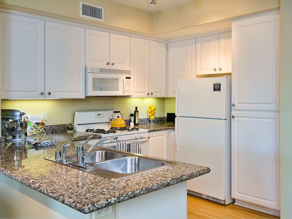 Classic Package I kitchen with white appliances, beige speckled granite countertop, white cabinetry, and hard surface flooring