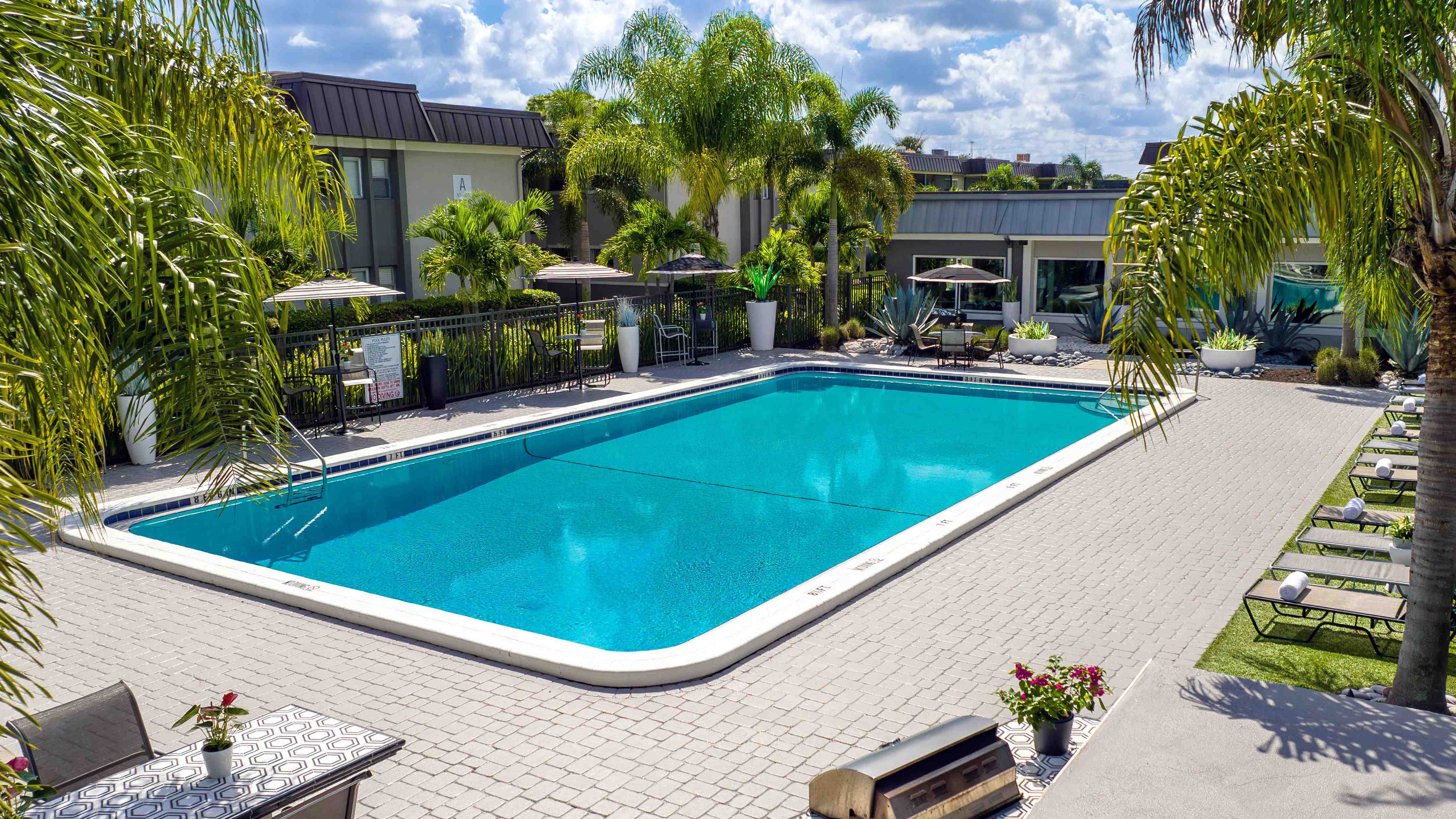 Soak up the sun at the resort-style pool surrounded by lush tropical landscaping, comfortable lounge seating, and shaded areas offering the perfect spot to relax and unwind.