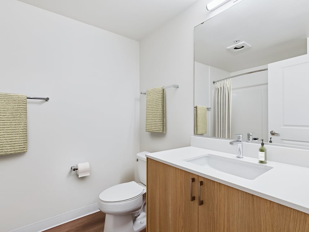 Renovated Package II bath with oak cabinetry, beige quartz countertops, and hard surface flooring