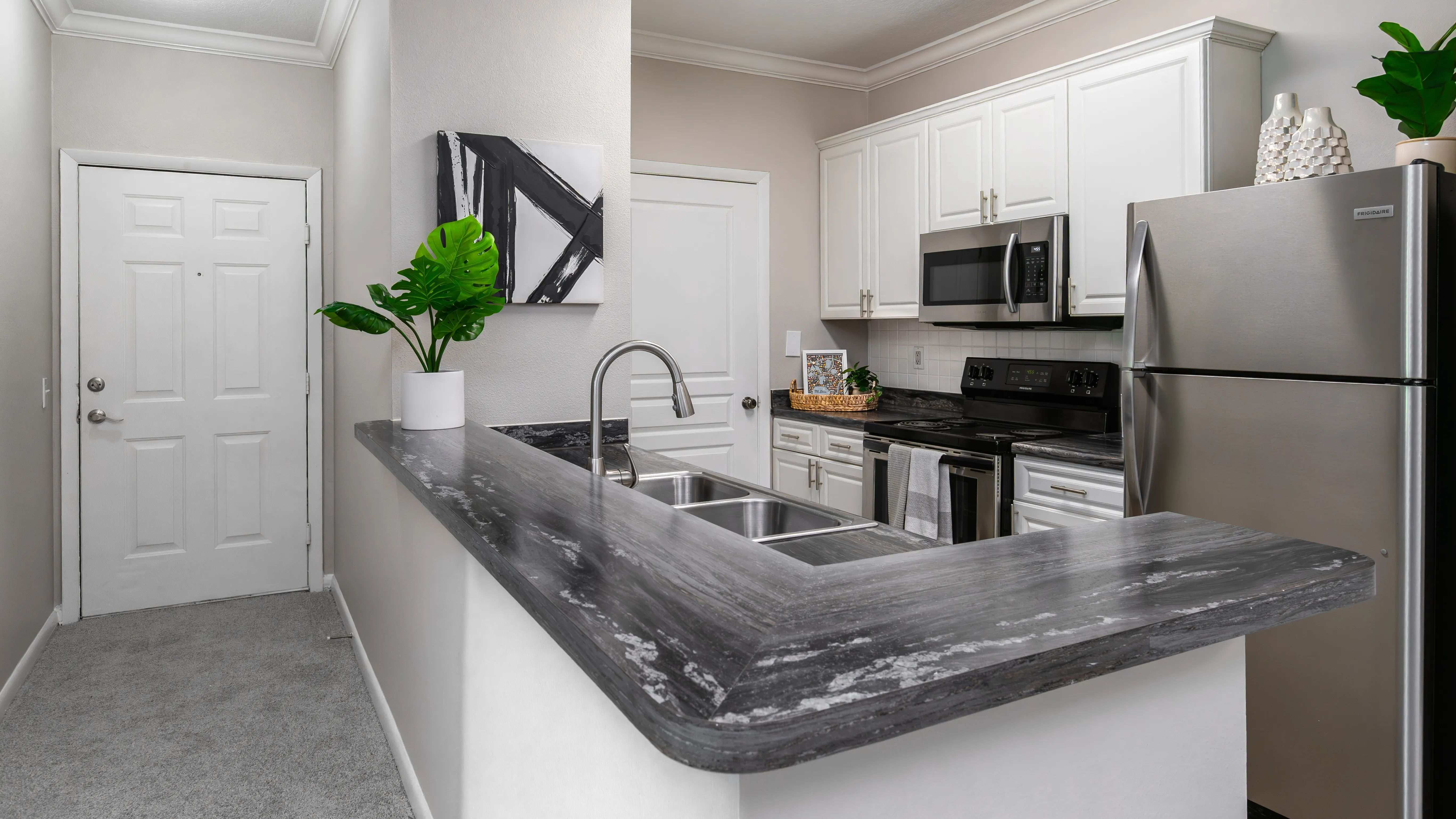 Whip up your favorite meals in this sleek kitchen, featuring stainless-steel appliances, modern white cabinetry, and a convenient breakfast bar perfect for casual dining.