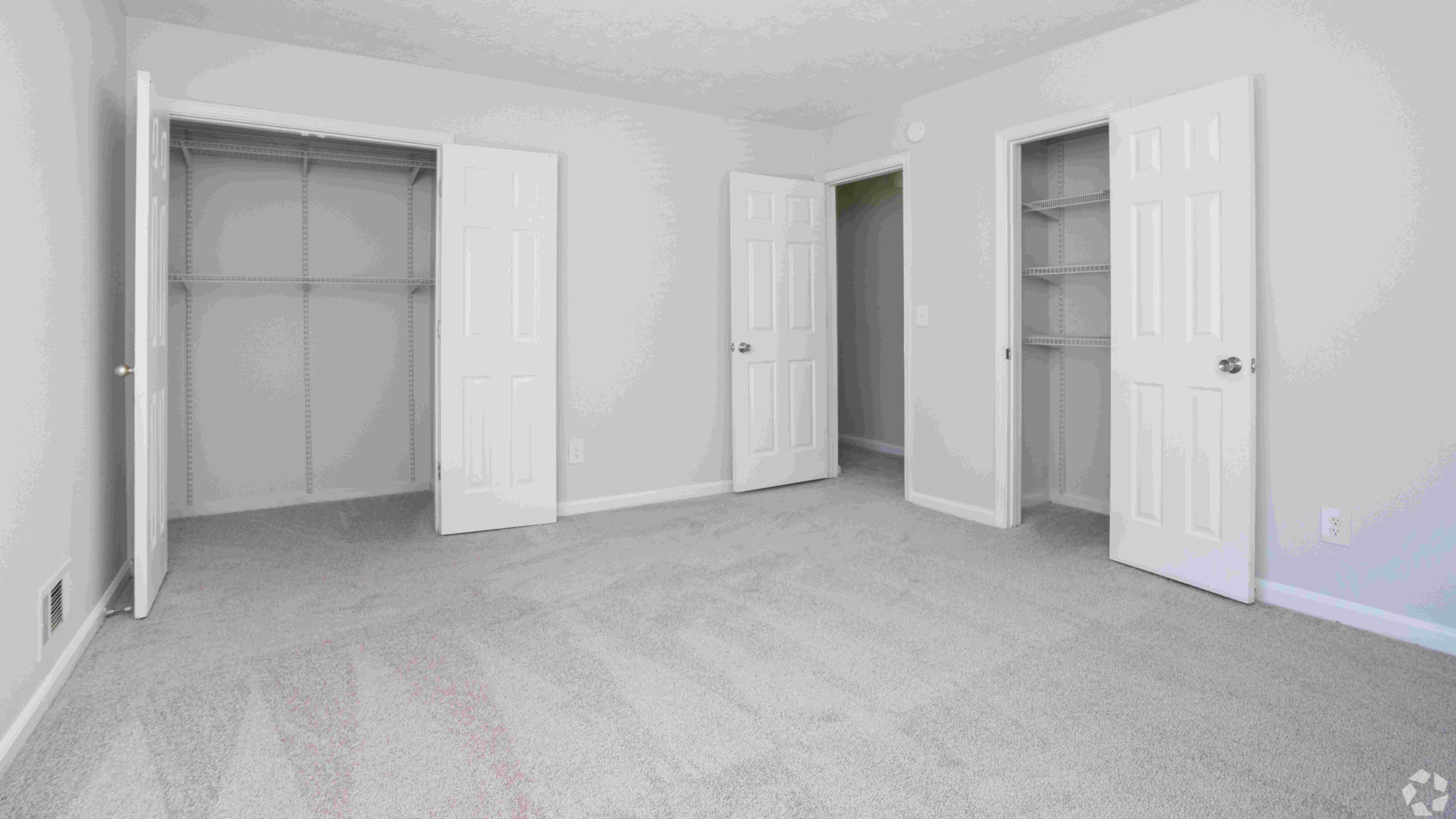 Spacious bedroom featuring ample closet space with built-in shelving and plush carpeting for added comfort.