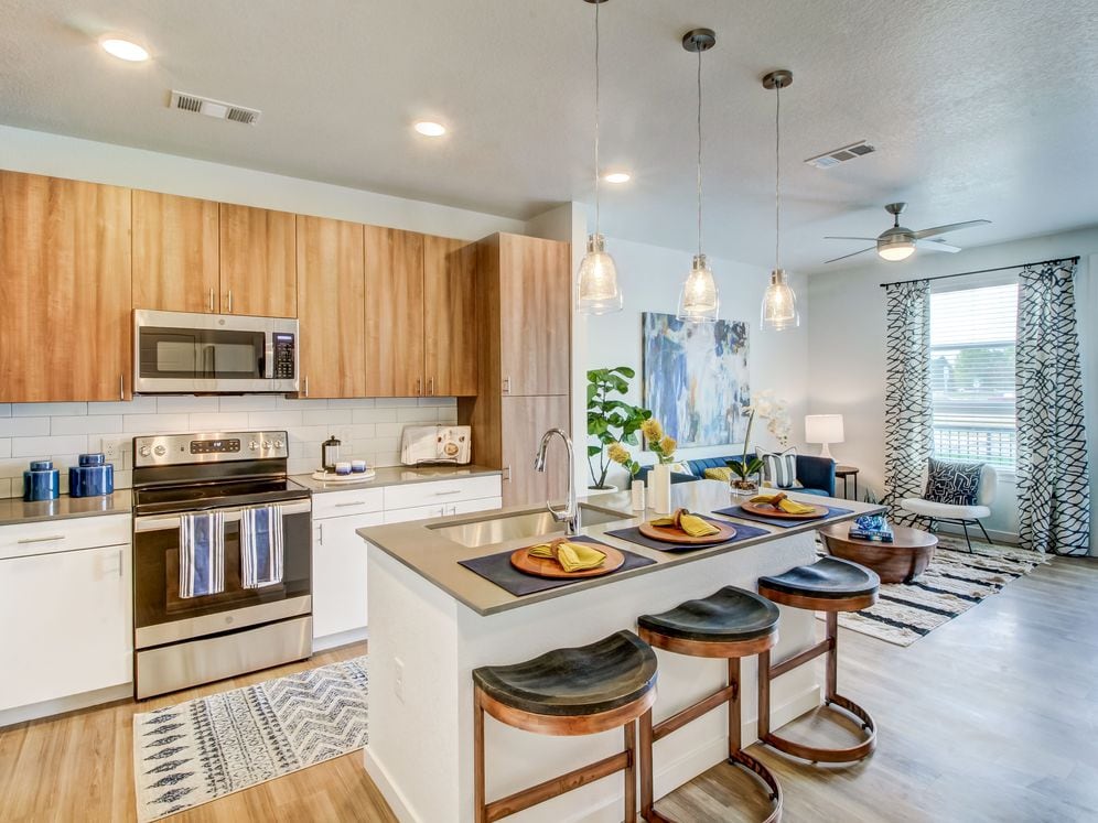 Kitchens feature oak upper and white lower cabinetry, grey quartz countertops, white subway tile backsplash, kitchen island or breakfast bar, and luxury vinyl plank flooring