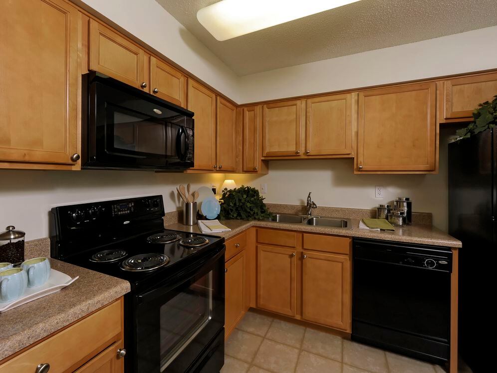 Classic Package II kitchen with oak cabinetry, beige laminate countertops, black appliances and tile flooring