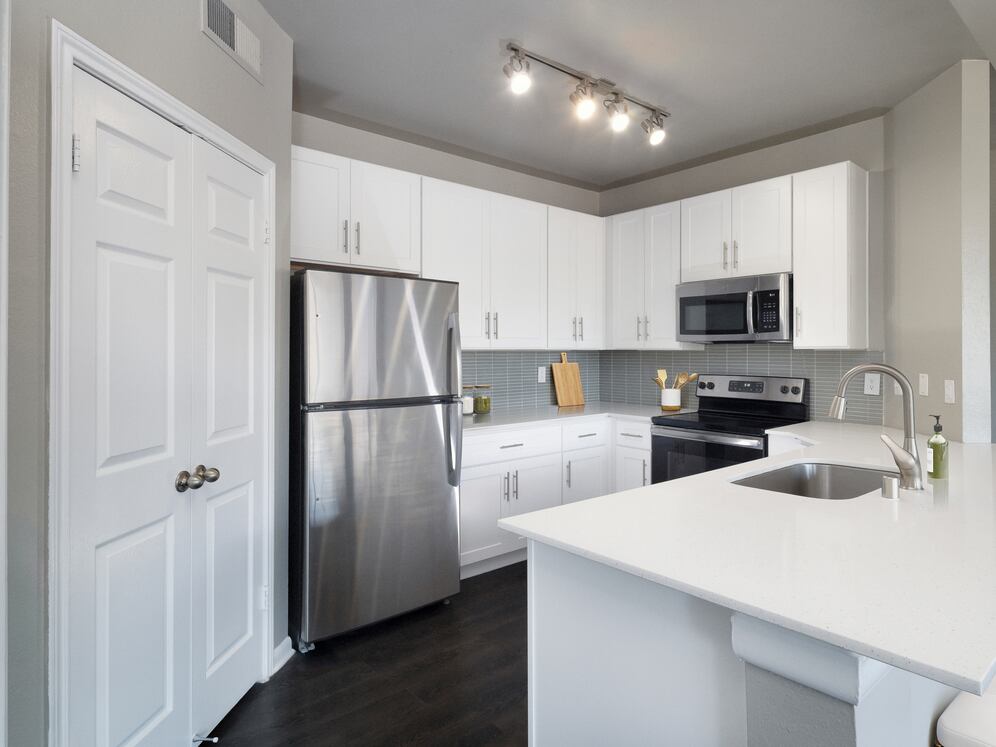 Classic Package II kitchen with stainless steel appliance, white quartz countertop, tile backsplash, white cabinetry, and hard-surface flooring
