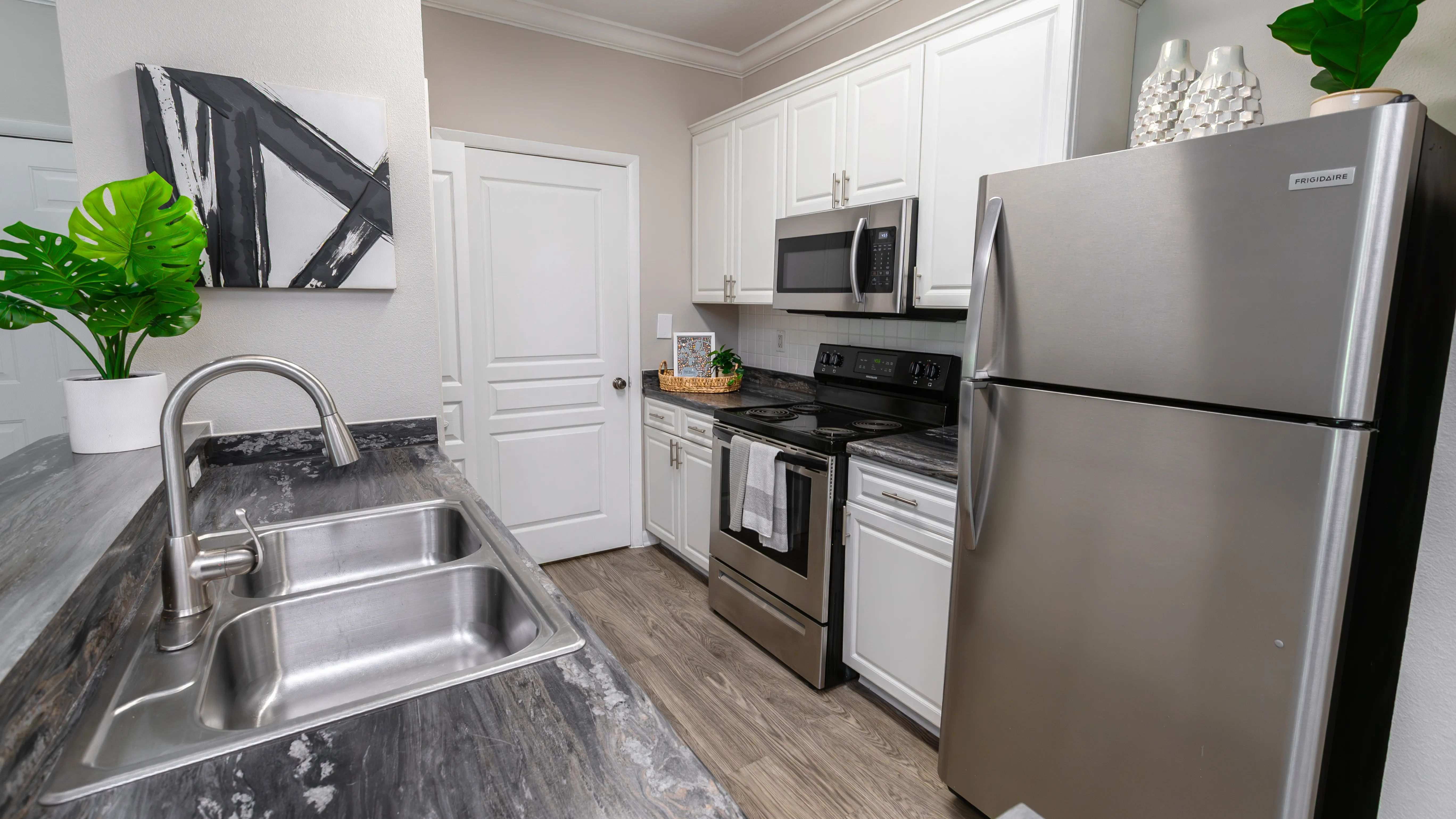 Cook, clean, and entertain with ease in this fully equipped kitchen,featuring stainless-steel appliances, white shaker cabinets, and wood-style flooring.