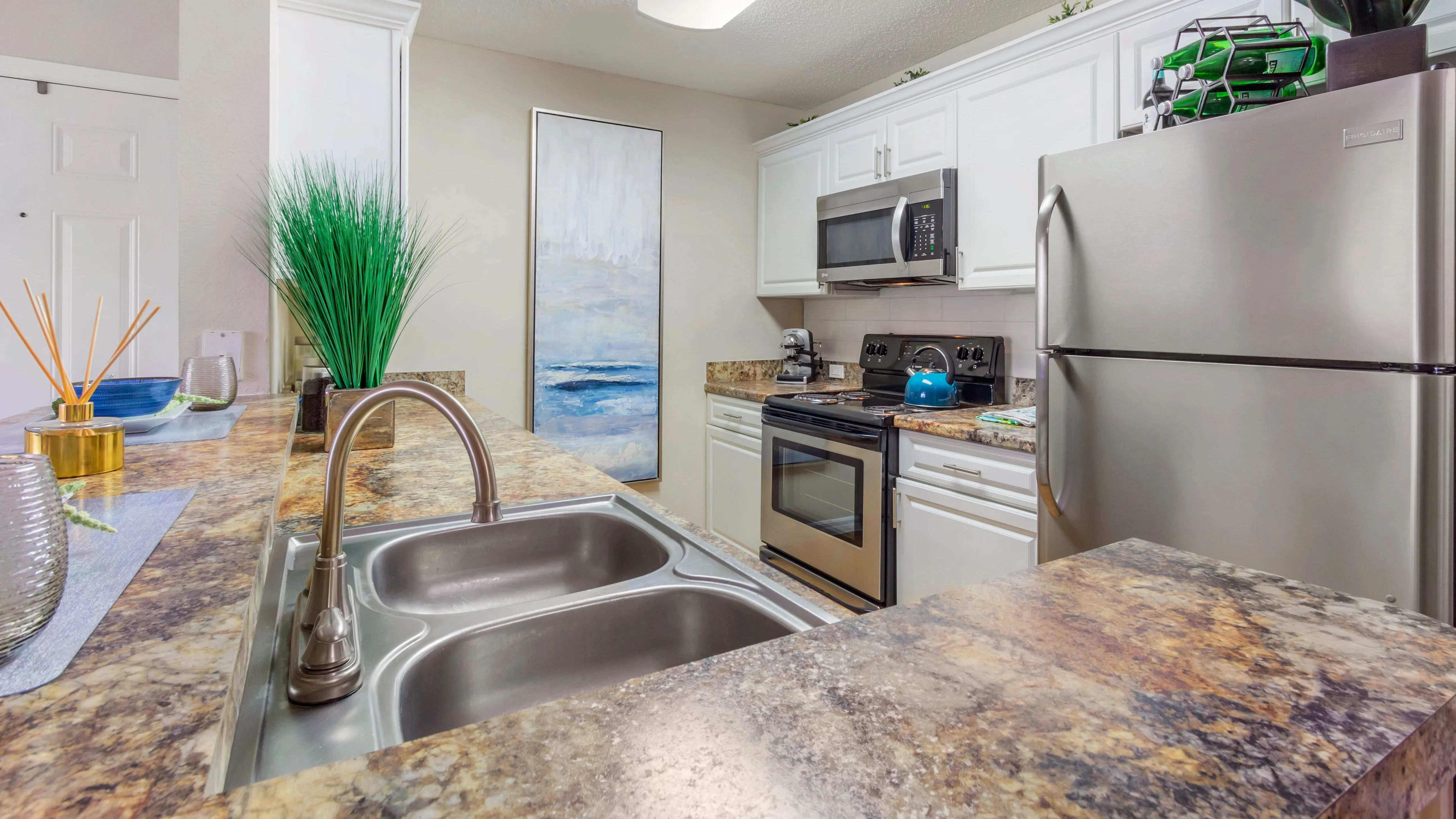 Cook and entertain in style with granite-inspired golden Mascarella countertops, sleek stainless steel appliances, and white cabinetry.