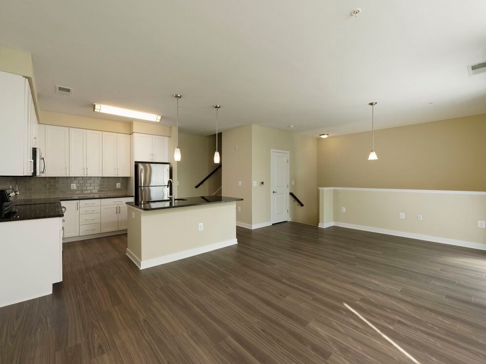 Townhome living area and open concept kitchen with granite countertops and tile backsplash, white shaker cabinetry, stainless steel appliances and hard surface flooring