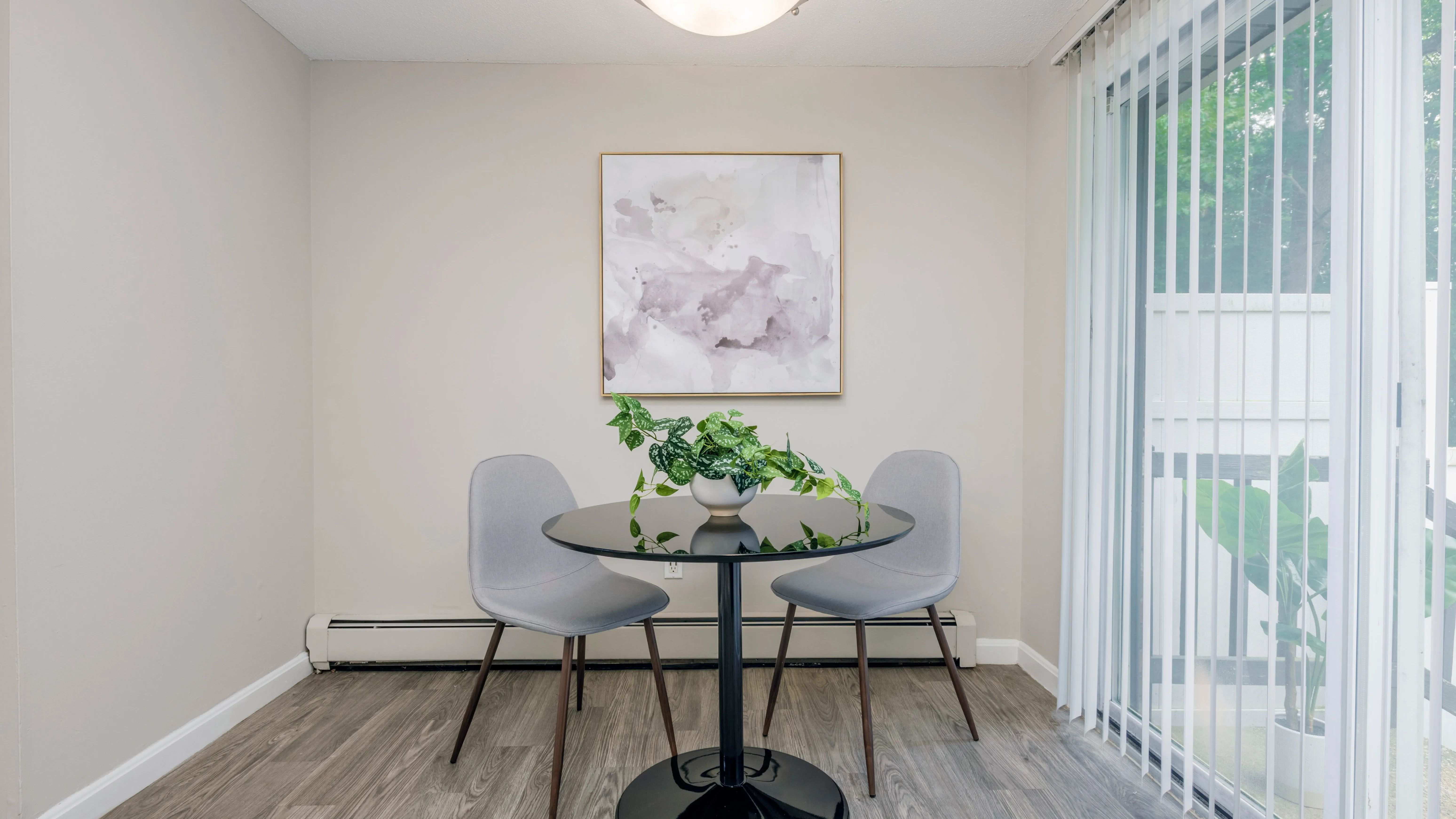 Elegant dining area in The Sycamore floor plans, providing a stylish space for meals next to sliding patio doors and a cozy baseboard heaters.
