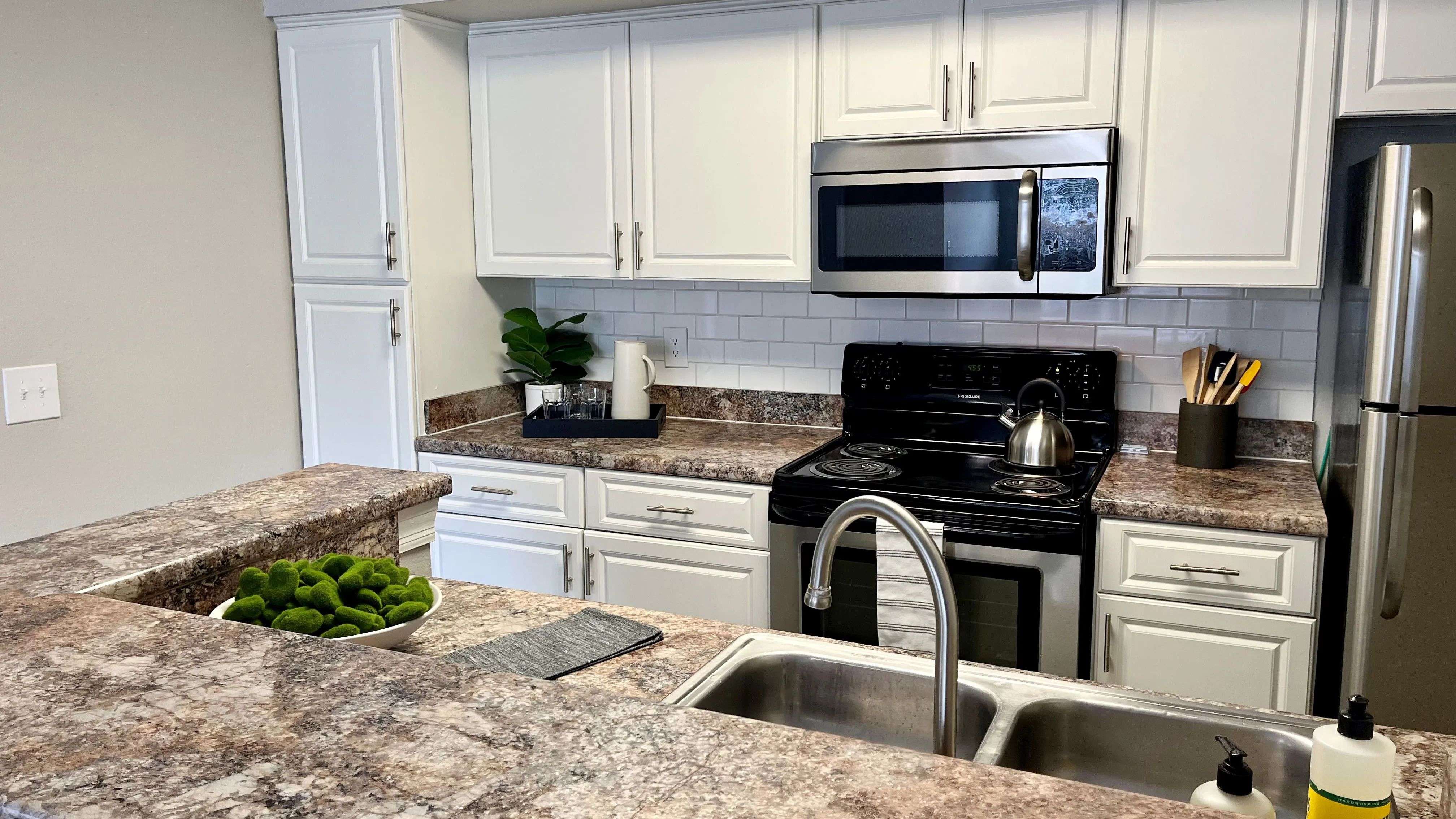 Kitchens that inspire gatherings with a granite-style countertop breakfast bar and modern stainless-steel appliances. 
