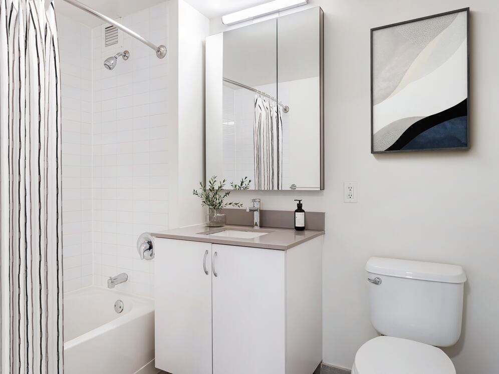 Renovated Package I bath with grey quartz countertop, white cabinetry, and hard-surface flooring (Representative Imagery)