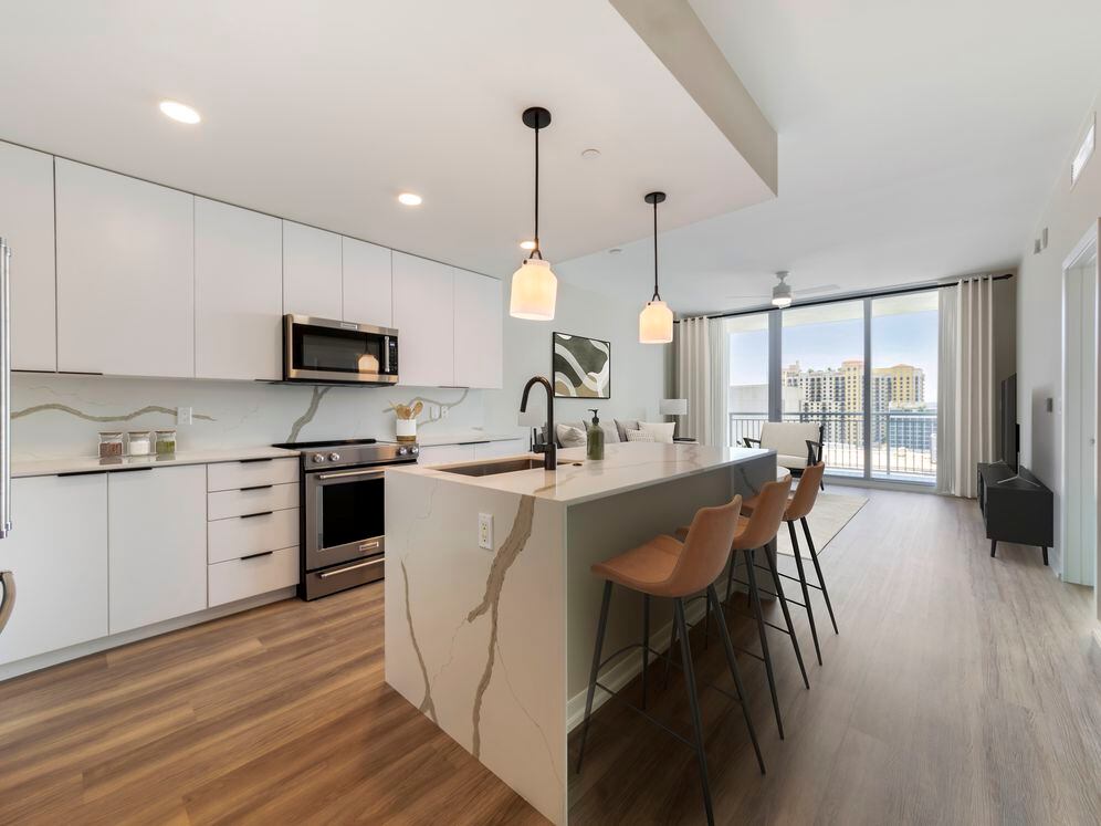 Tower Building - Renovated kitchen with stainless steel appliances, marbled white quartz countertops, light grey cabinetry, and hard surface flooring