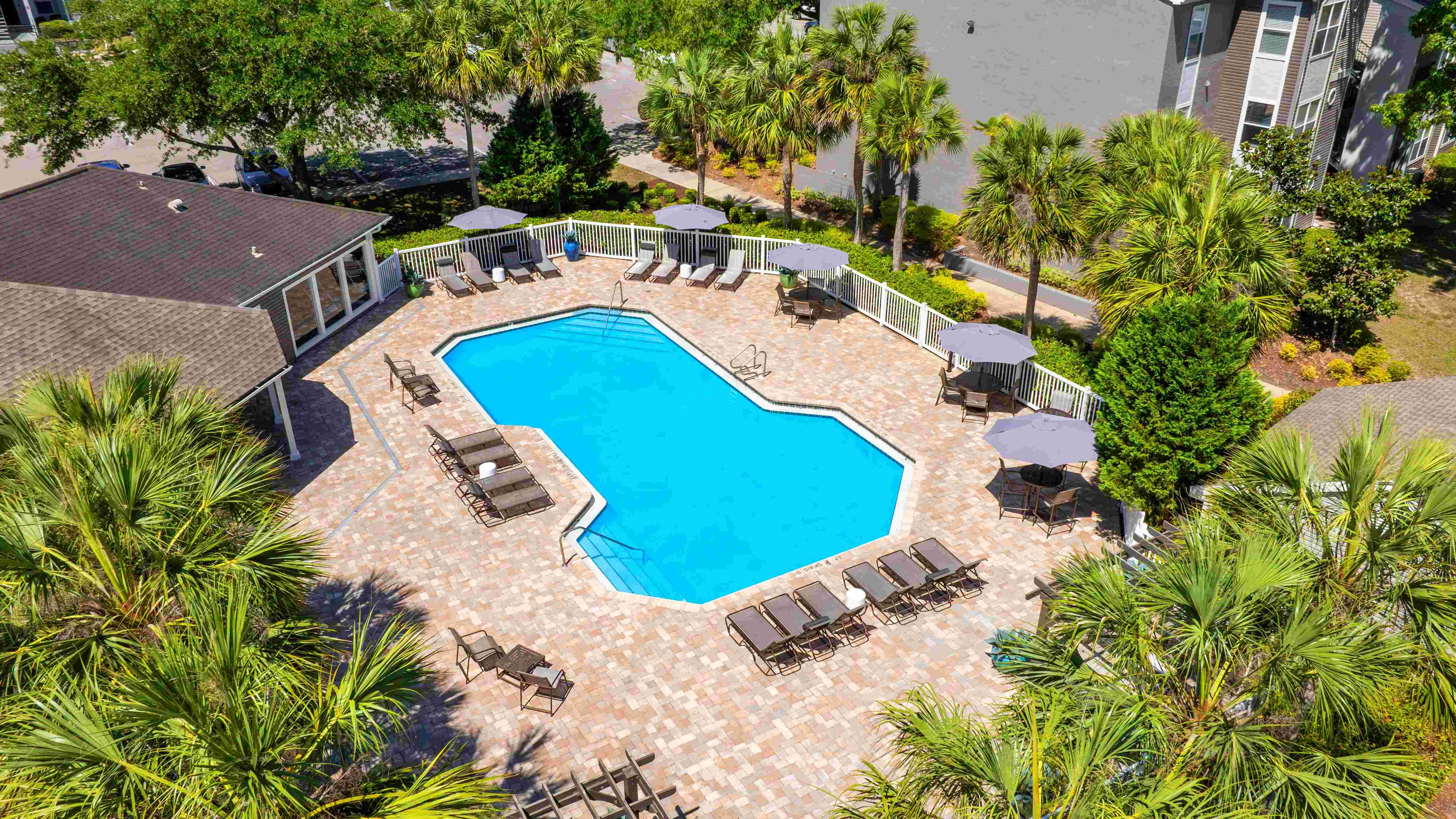 A stunning aerial look at The Enclave at Huntington Woods' sparkling swimming pool—complete with spacious sundeck, lounge chairs, and shaded seating for the perfect day under the Florida sun.