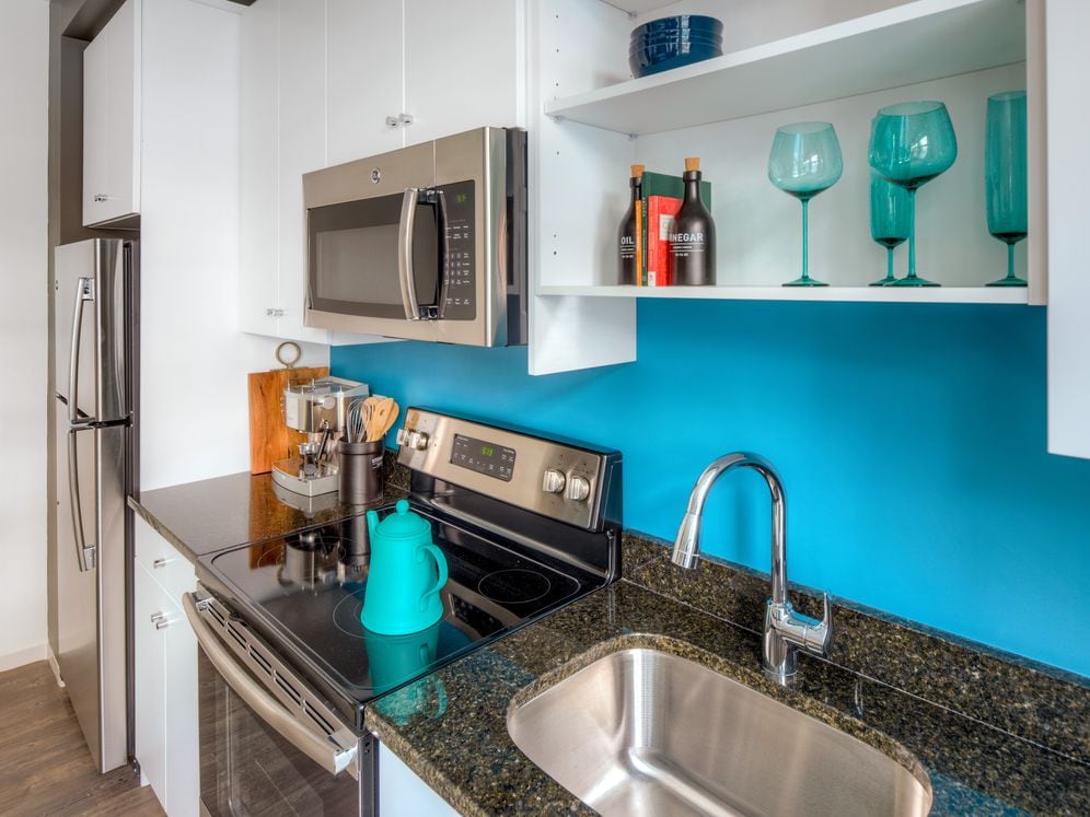 Kitchen with white cabinetry, granite countertops, stainless steel appliances and hard surface flooring