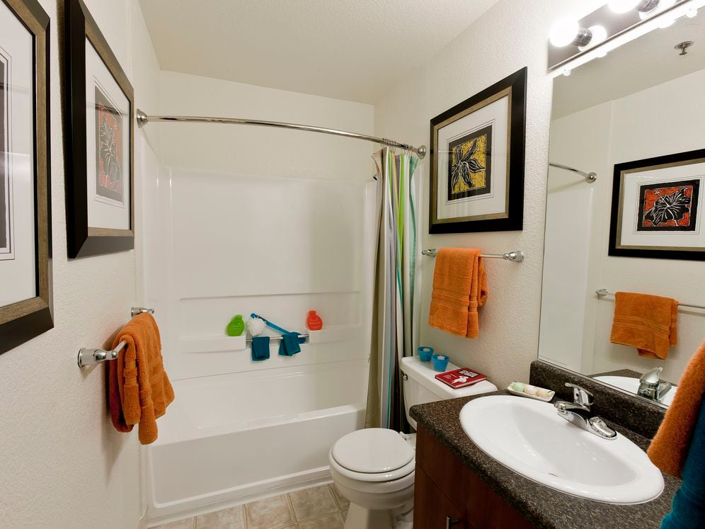 Bathroom with cherry cabinetry, tile flooring and shower and bath with white tile backsplash