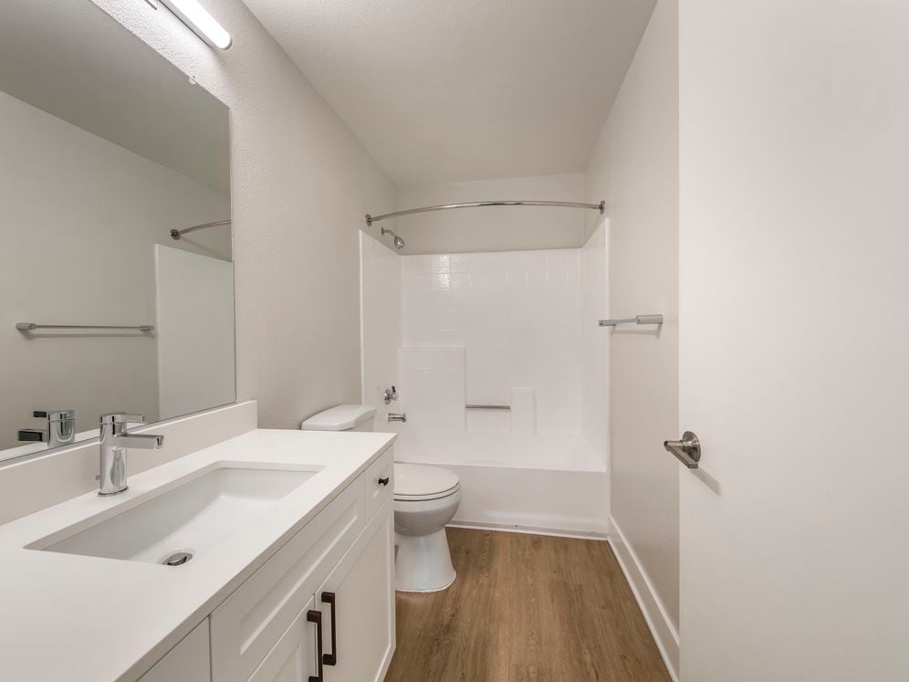 Renovated Package I bath with white quartz countertops, white cabinetry, and hard surface flooring