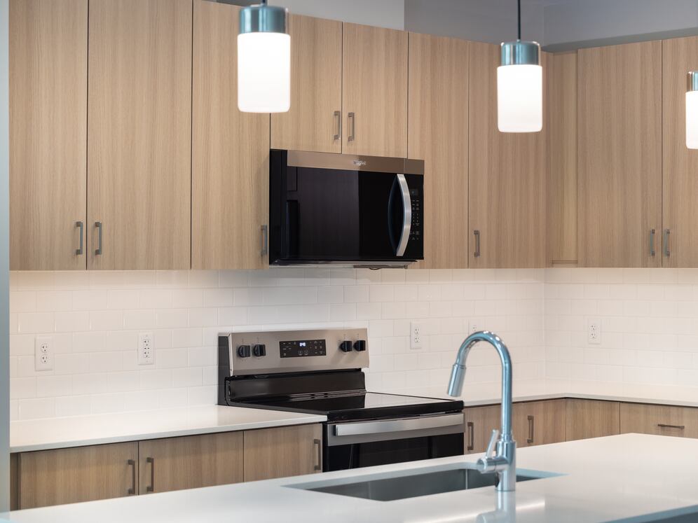 New West Phase - Finish Package IV Kitchen with oak cabinetry, white granite countertops, white tile backsplash, pendant lighting and stainless steel appliances