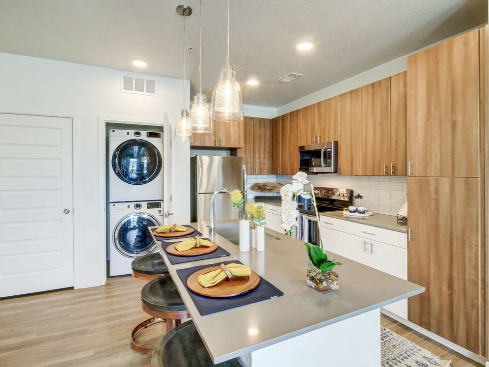 Kitchens feature oak upper and white lower cabinetry, grey quartz countertops, white subway tile backsplash, kitchen island or breakfast bar, and luxury vinyl plank flooring