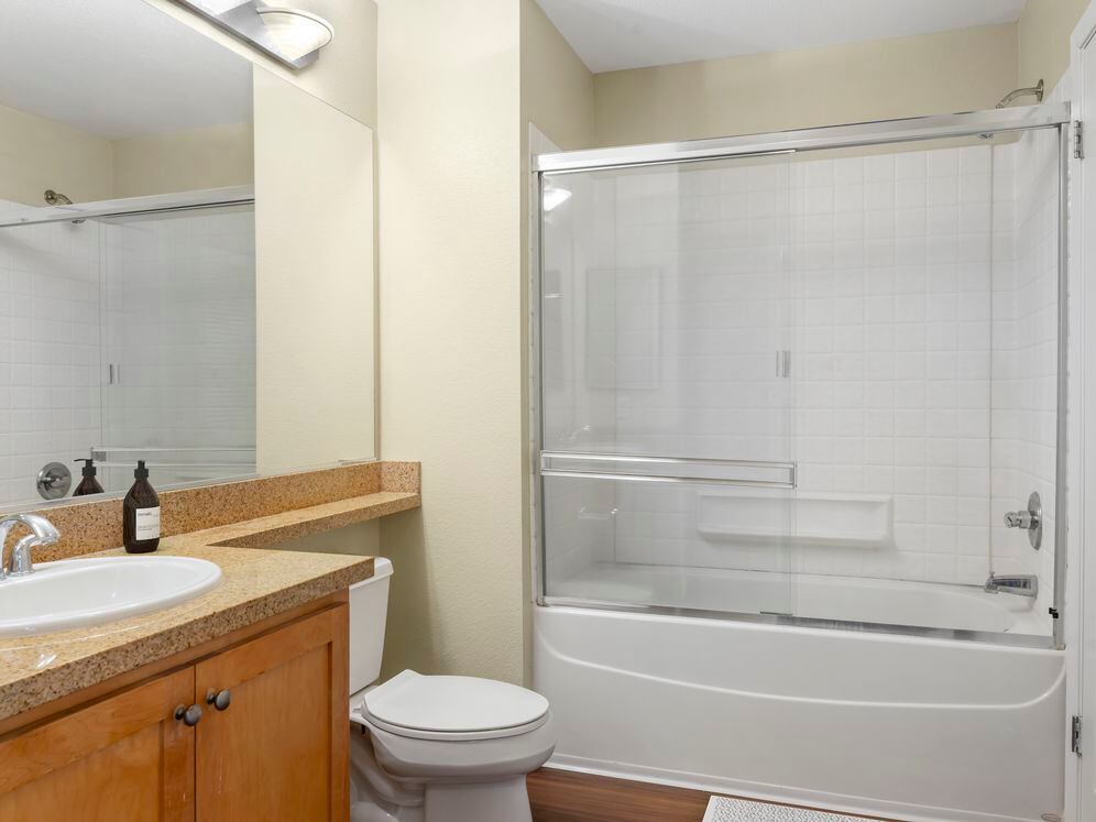 Classic Package II bath with oak cabinetry, beige speckled laminate countertops, and hard surface flooring