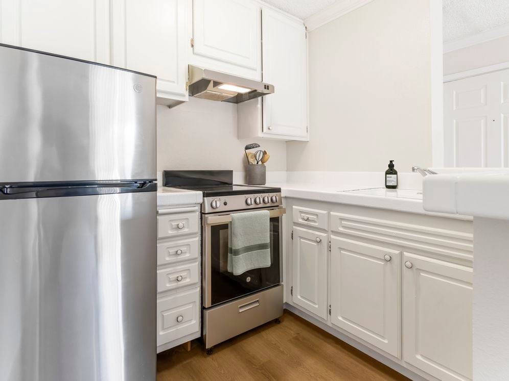 Classic Package II kitchen with stainless steel appliances, white tile countertops, white cabinetry, and hard surface flooring