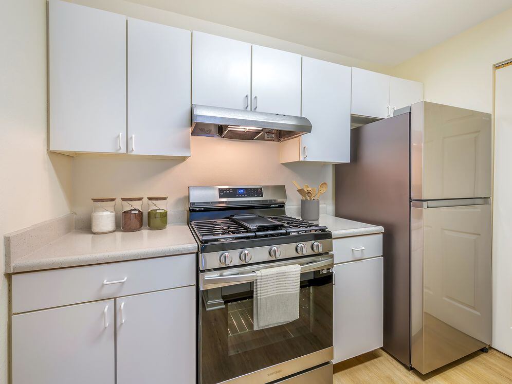 Classic Package II kitchen with stainless steel appliances, white laminate countertops, white cabinetry, and hard surface flooring