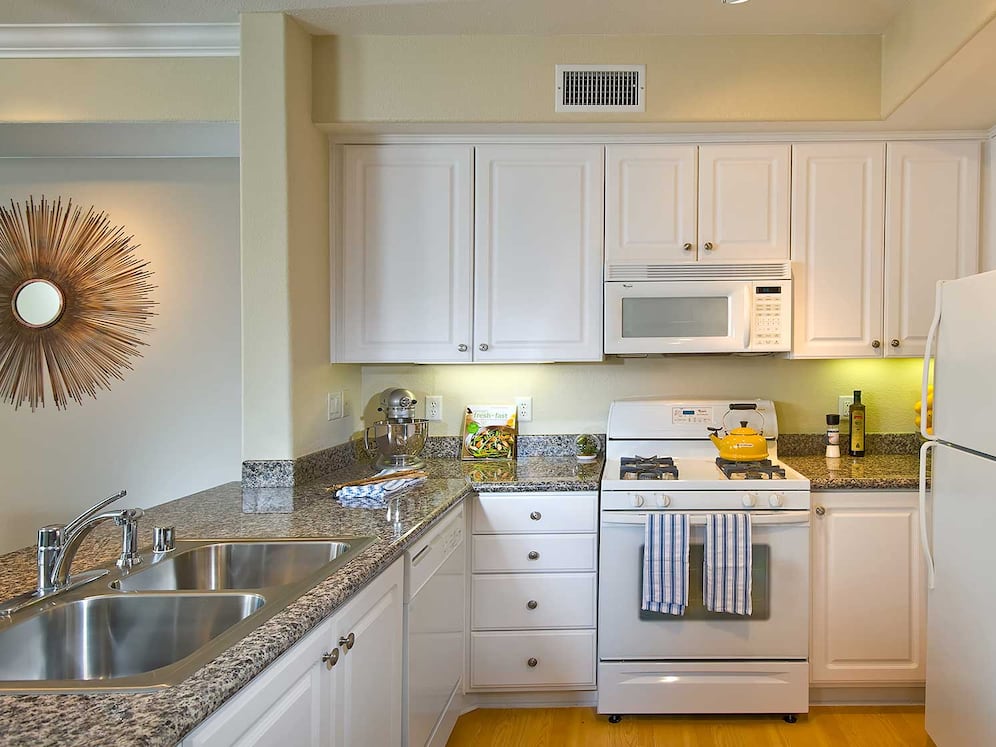 Classic Package I kitchen with white appliances, beige speckled granite countertop, white cabinetry, and hard surface flooring