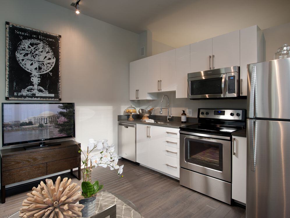 Open concept kitchen with white cabinetry, quartz countertops, stainless-steel appliances and hard surface flooring