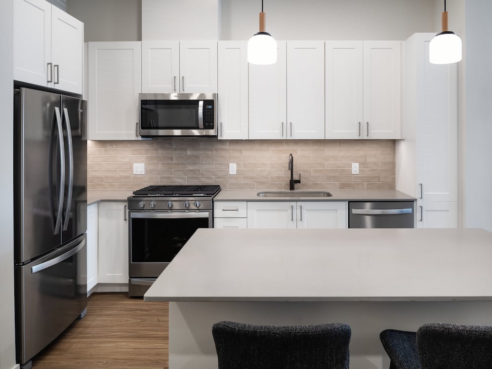 Upgrade Collection Kitchen with white shaker cabinetry, grey quartz countertops, beige tile backsplash, and stainless steel appliances