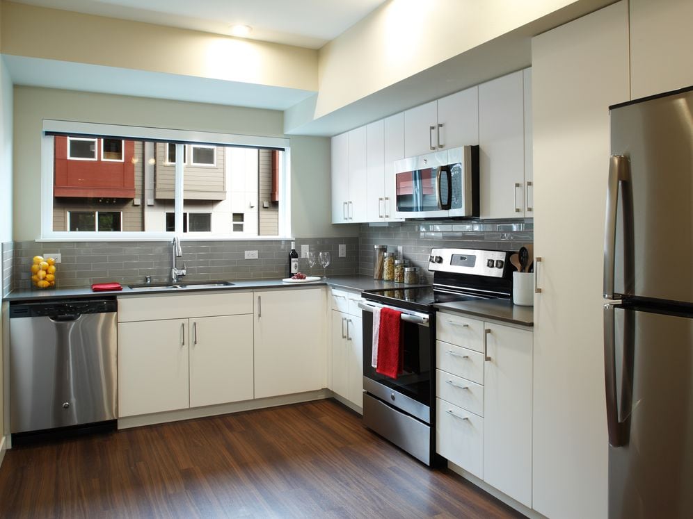 Phase I - Townhome Kitchen with white cabinetry, grey tile backsplash, stainless appliances, grey quartz countertops, and hard surface flooring