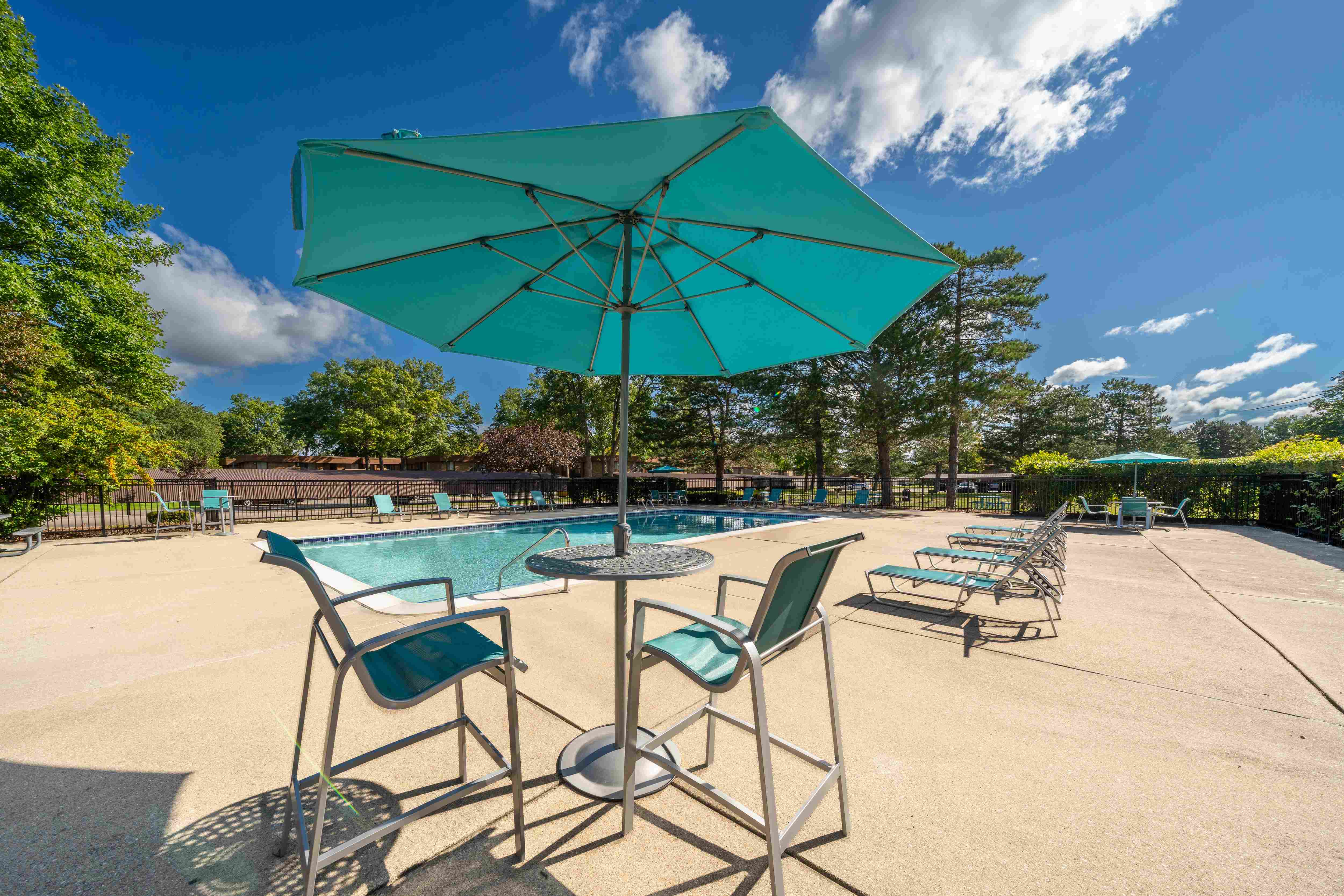 Heated pool equipped with comfy lounge chairs at Westwood Village Apartments in Westland, MI