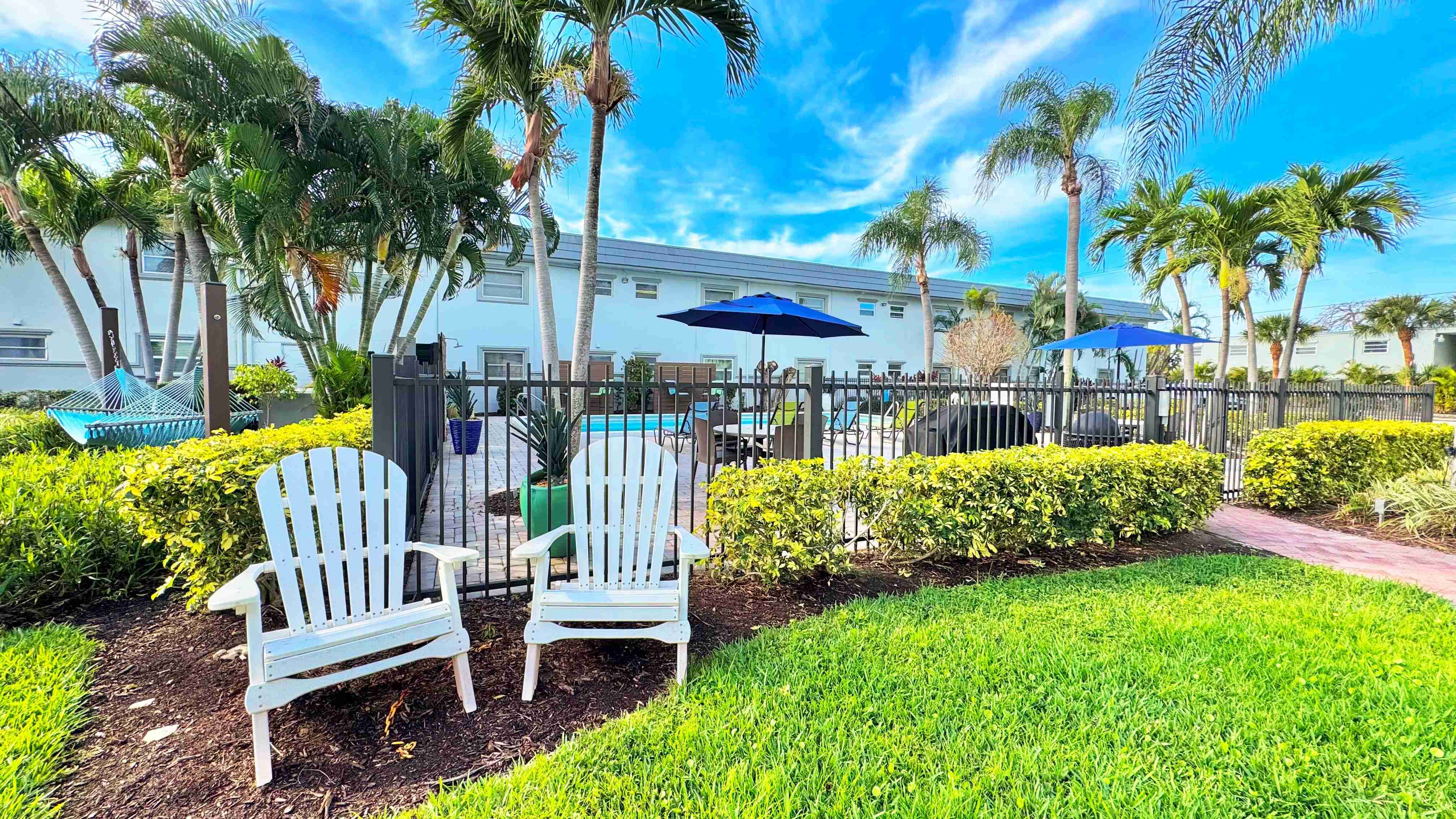 Enjoy the best of outdoor living with cozy Adirondack chairs and lush landscaping.