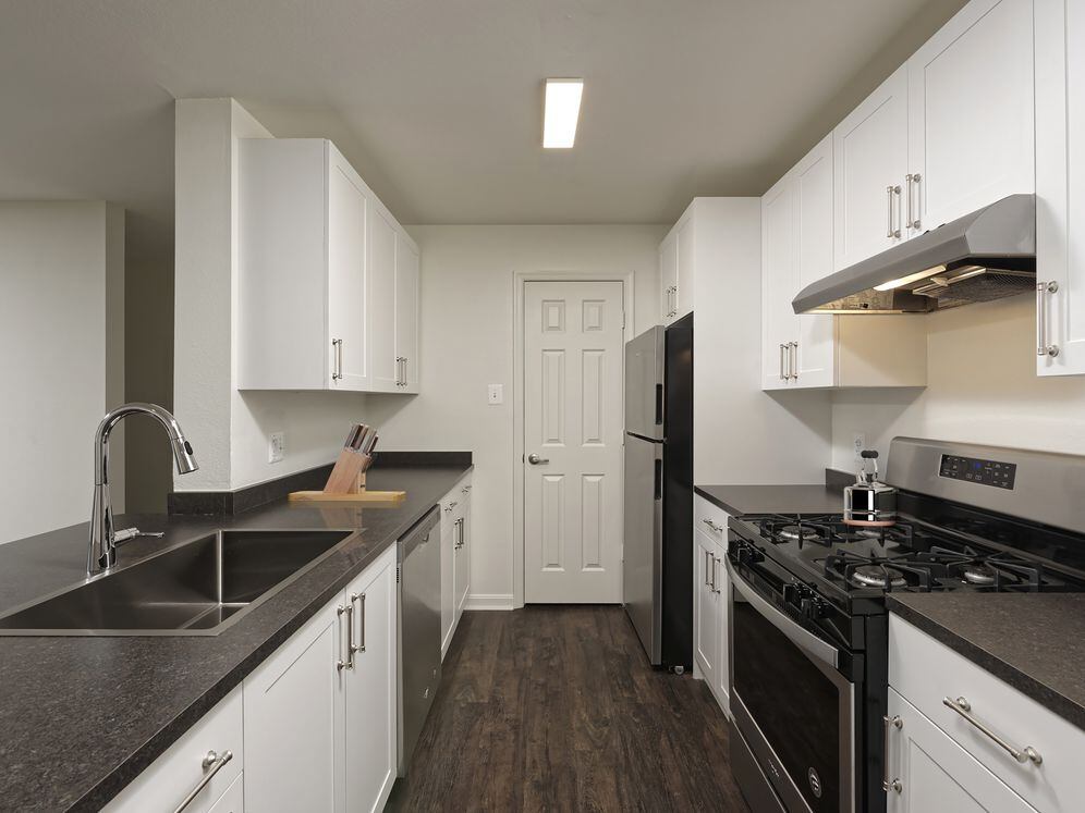 Renovated Package II kitchen with white cabinetry, dark grey laminate countertops, and stainless steel appliances, and hard surface flooring
