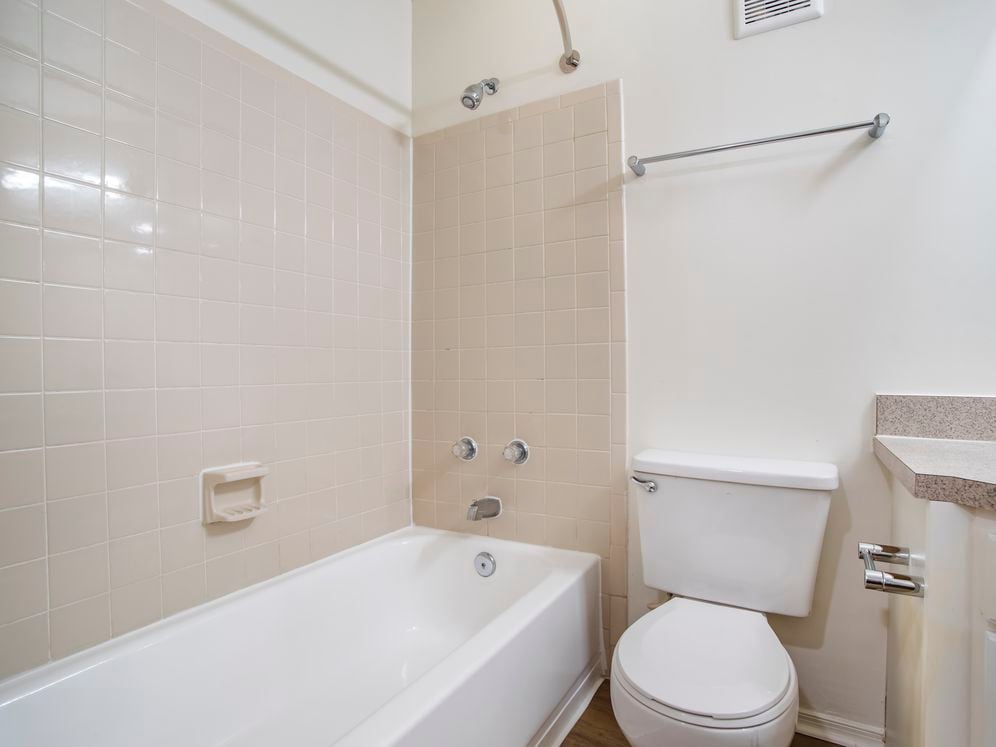 Renovated Package II bath with laminate countertops, white cabinetry, and hard surface flooring