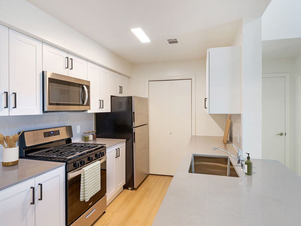New Apartments kitchen with new stainless steel appliances, grey quartz countertops, grey subway tile backsplash, and hard surface flooring