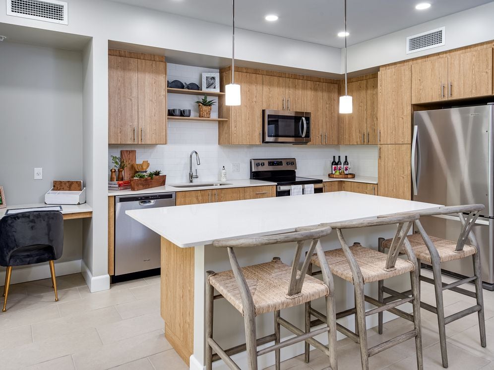 Open concept kitchen with quartz countertop, island, stainless steel appliances, tile backsplash and work from home nook