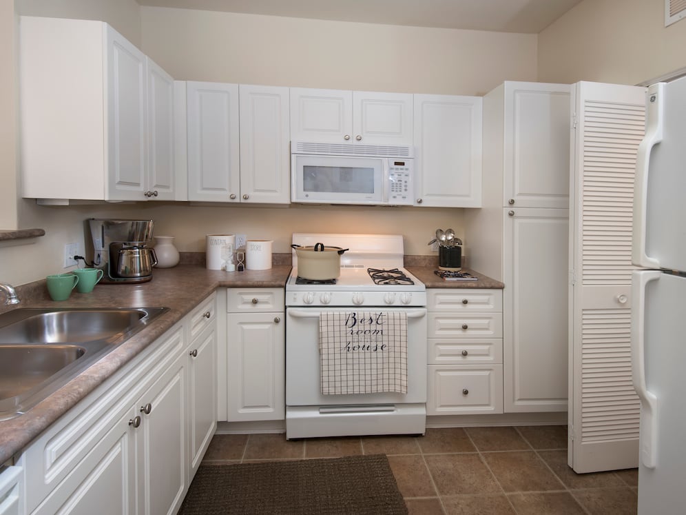 Classic Package I kitchen with white cabinetry, white appliances, laminate countertops, and tile flooring
